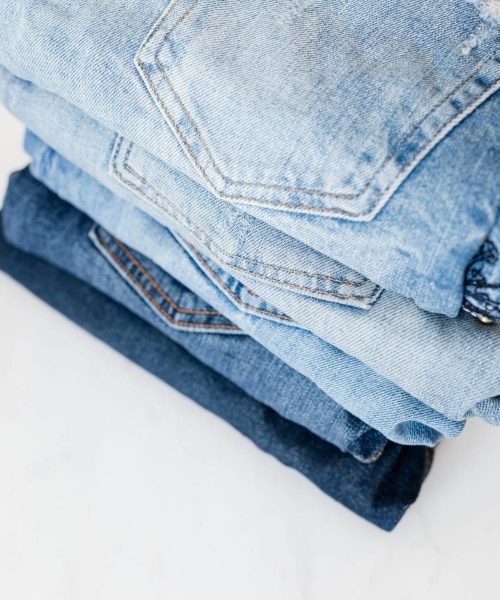 stack-of-jeans-on-white-marble-surface-4210857